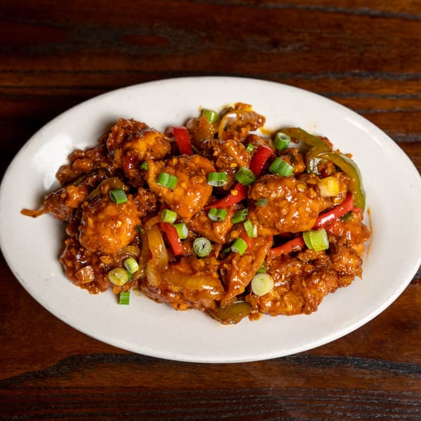 Noorani Kabab House's chili chicken, a vibrant Indian dish with red and green peppers and scallions.