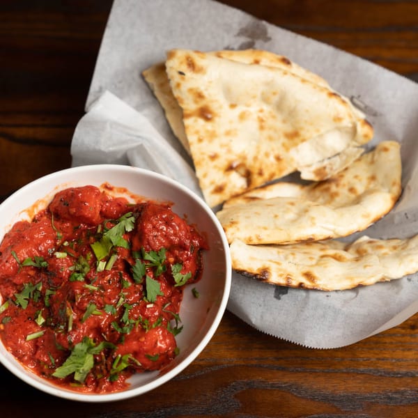 Noorani Kabab House's chicken tikka masala, garnished with cilantro, served with naan bread.